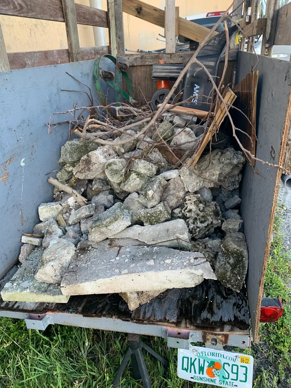 Trailer loaded with concrete, wood, branches, and other renovation debris for removal