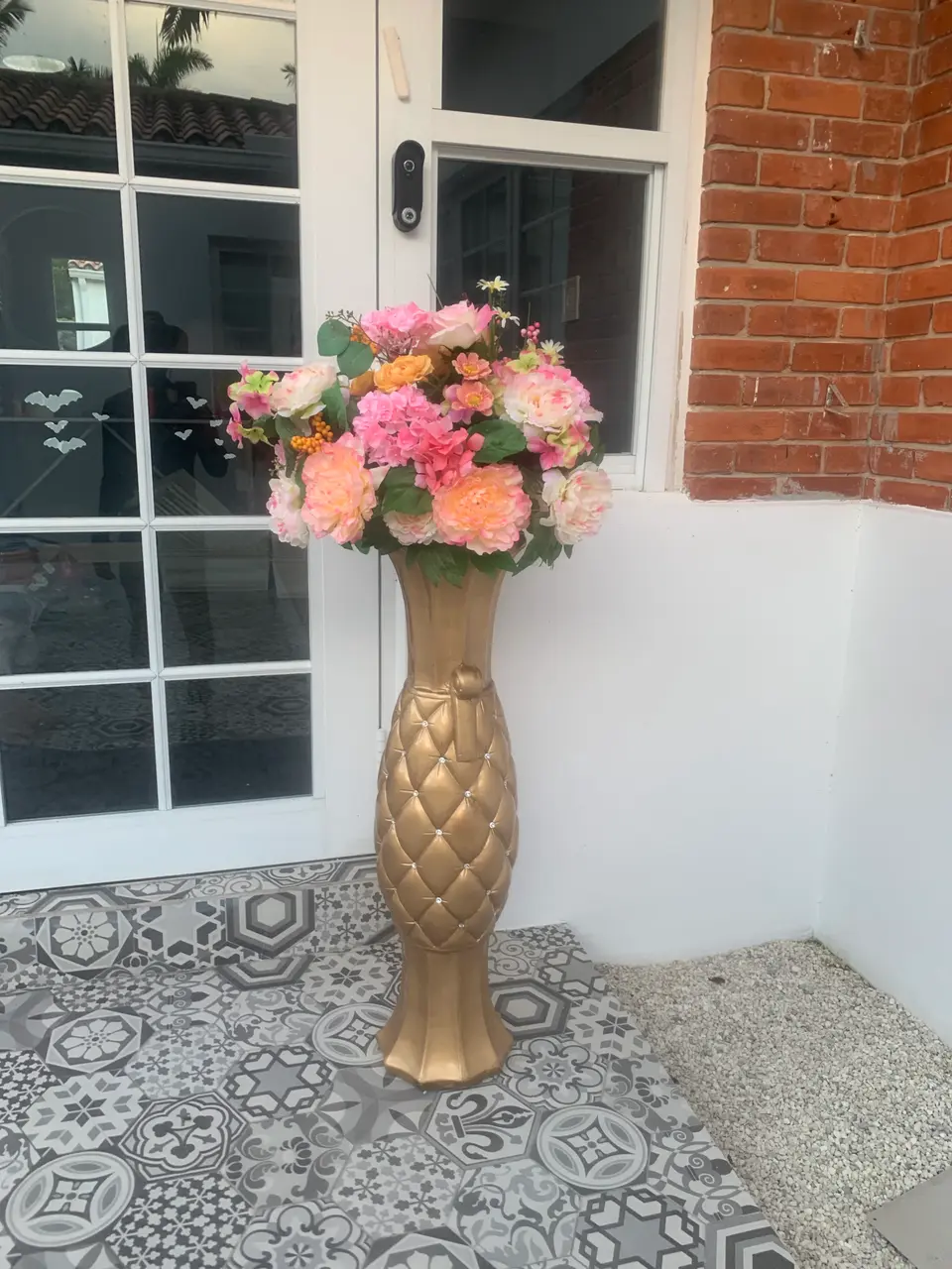 Large pink, peach, and cream floral arrangement in a tall gold decorative vase