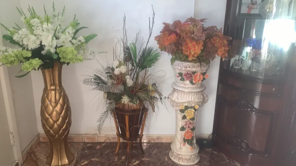 Three ready-made floral arrangements displayed in decorative floor vases and planters