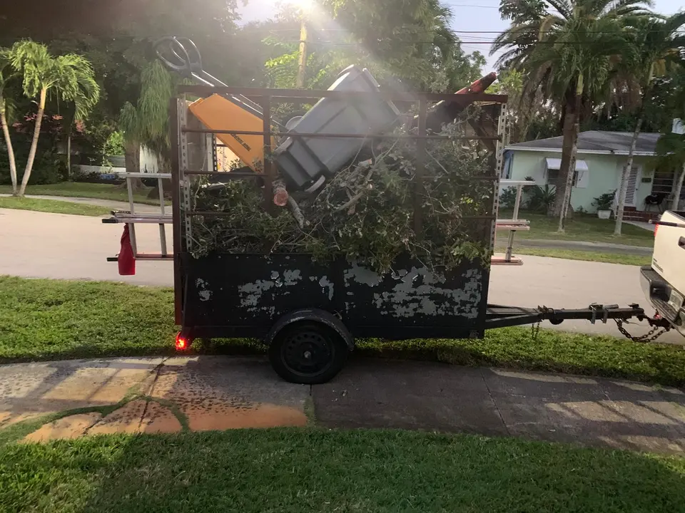 Utility trailer loaded with yard debris and household items during a residential junk removal job